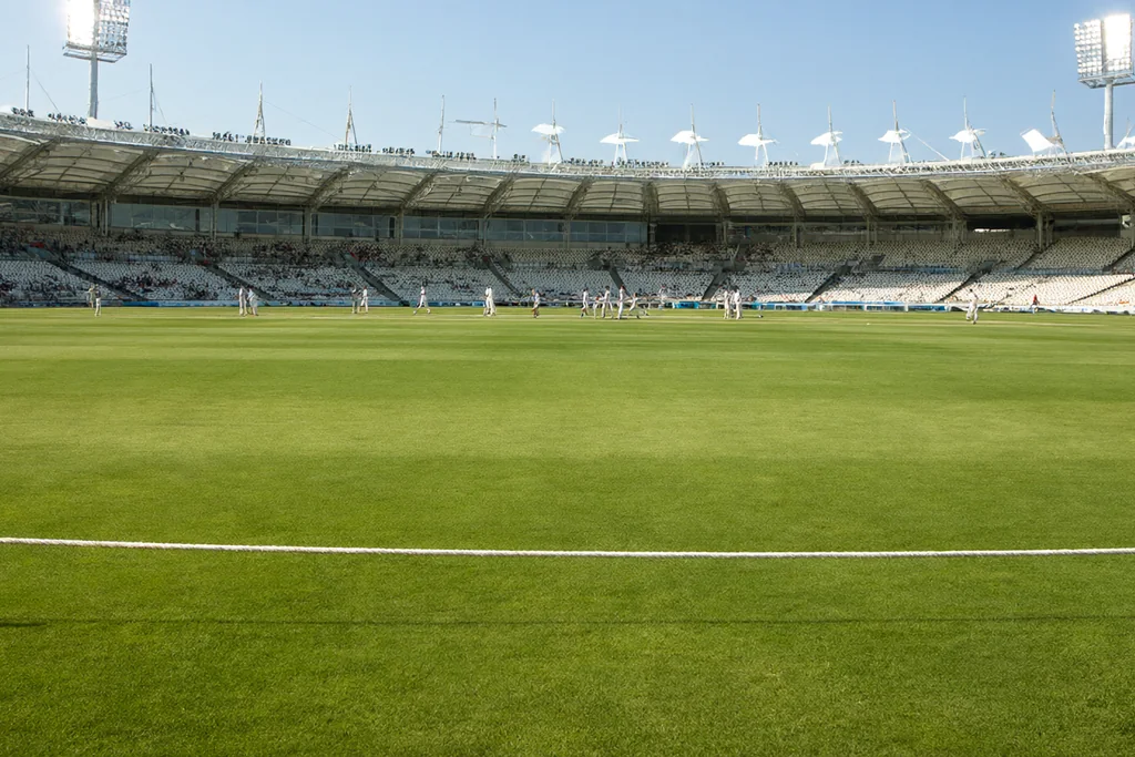 A boundary rope and green outfield in an empty stadium