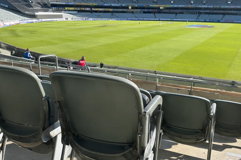 An empty stadium seat overlooking a green cricket field