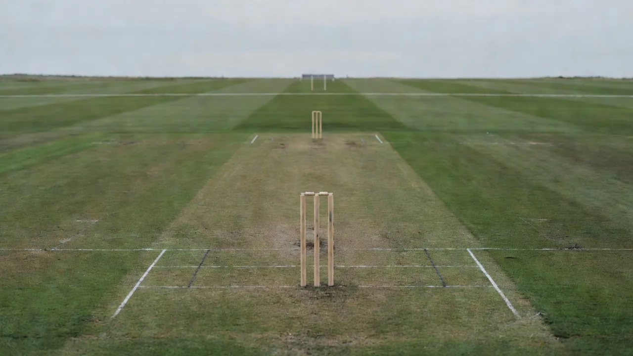 An empty cricket pitch viewed from behind the stumps